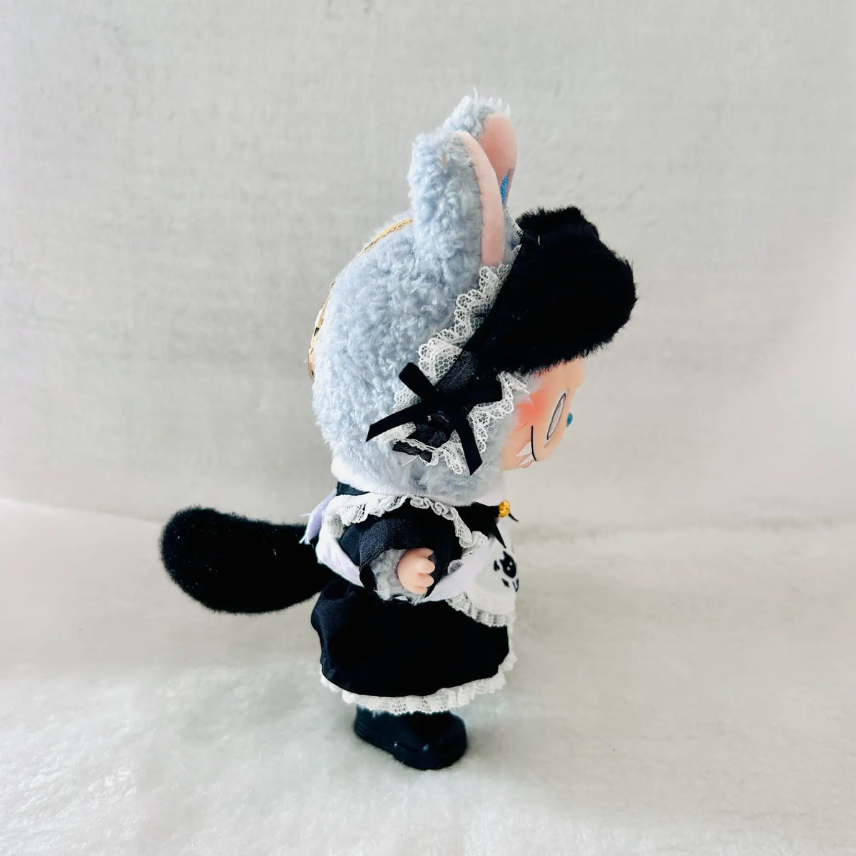 A Labubu plush doll wearing a black maid dress with cat tail, and white lace trim arpon.