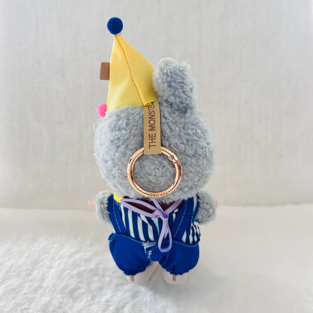 A back view of a Labubu wearing a yellow jester hat, blue striped top and a blue overalls.