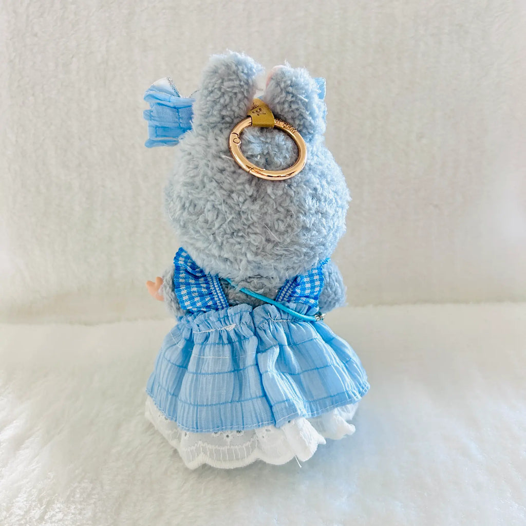 The back of a Labubu doll wearing a blue gingham dress with white lace trim and a gold ring accessory on its back.