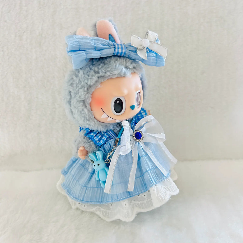 A cute Labubu plush doll wearing a light blue plaid dress with white lace trim, a large white bow, and a blue bunny keychain.