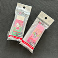 Two packaged PVC erasers featuring Hello Kitty and Sanrio characters, displayed on a dark textured background.