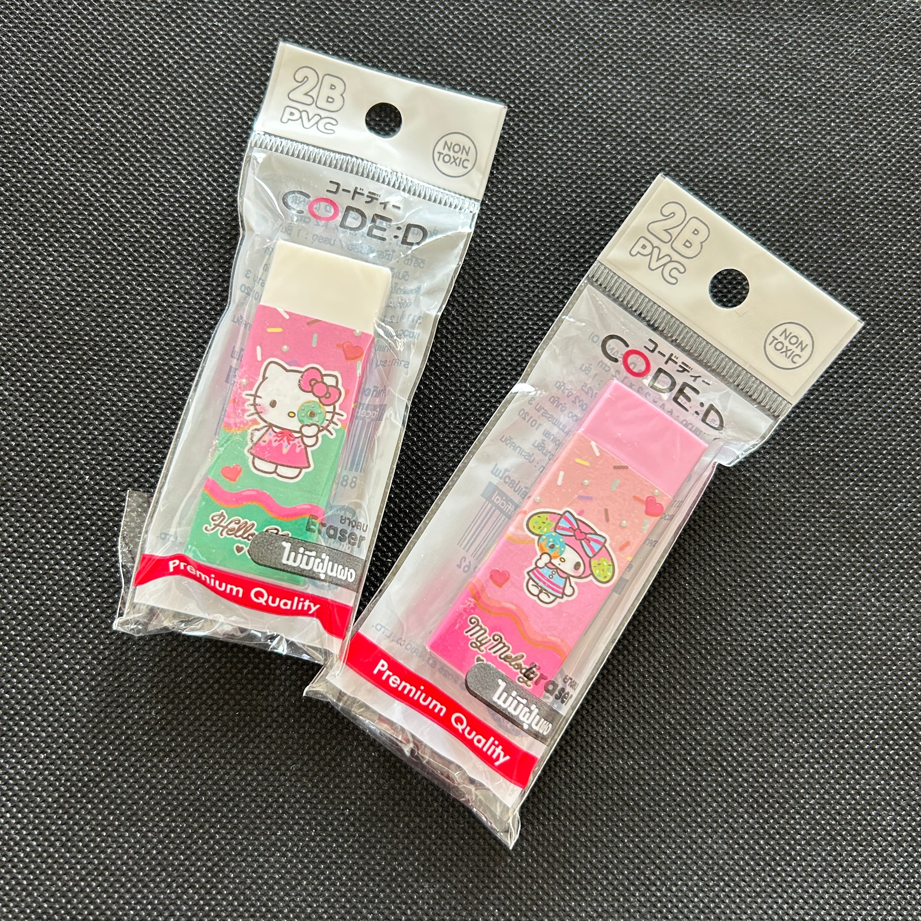 Two packaged PVC erasers featuring Hello Kitty and Sanrio characters, displayed on a dark textured background.