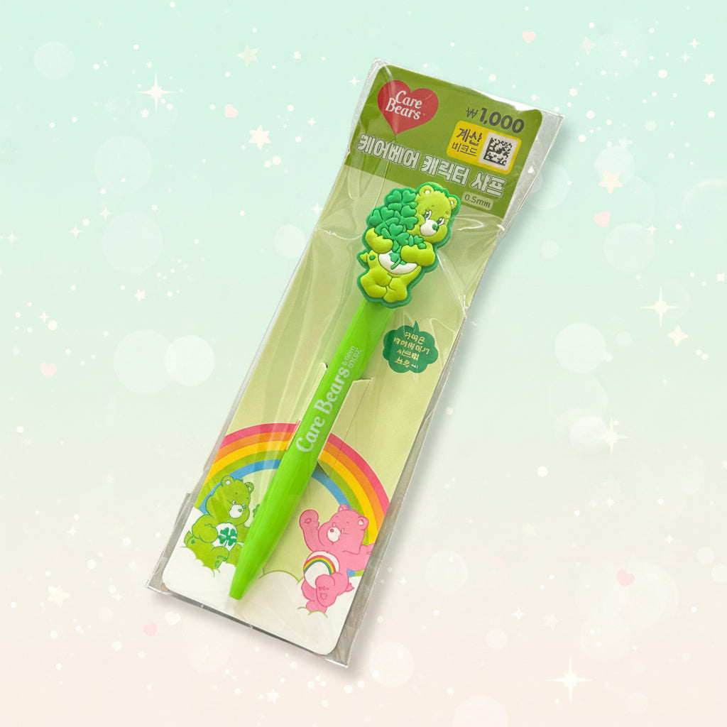 A green Care Bears toothbrush in its original retail packaging, displayed diagonally on a split gray and black textured surface.