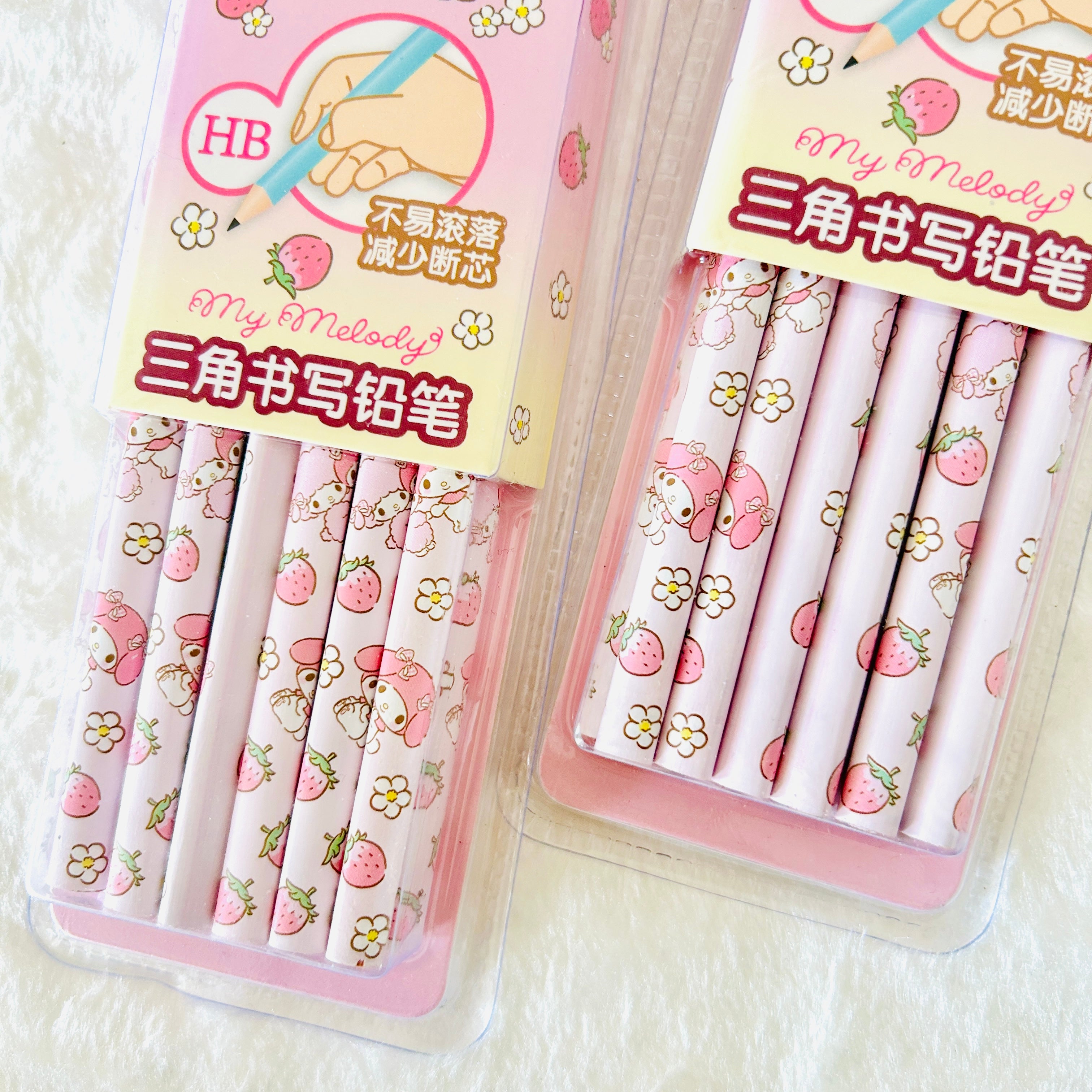 Two packages of pink strawberry-themed HB pencil erasers on a white textured background. The packages feature cute illustrations of a pink character with a strawberry hat, flowers, and strawberries, with Chinese text and 'My Melody' branding.