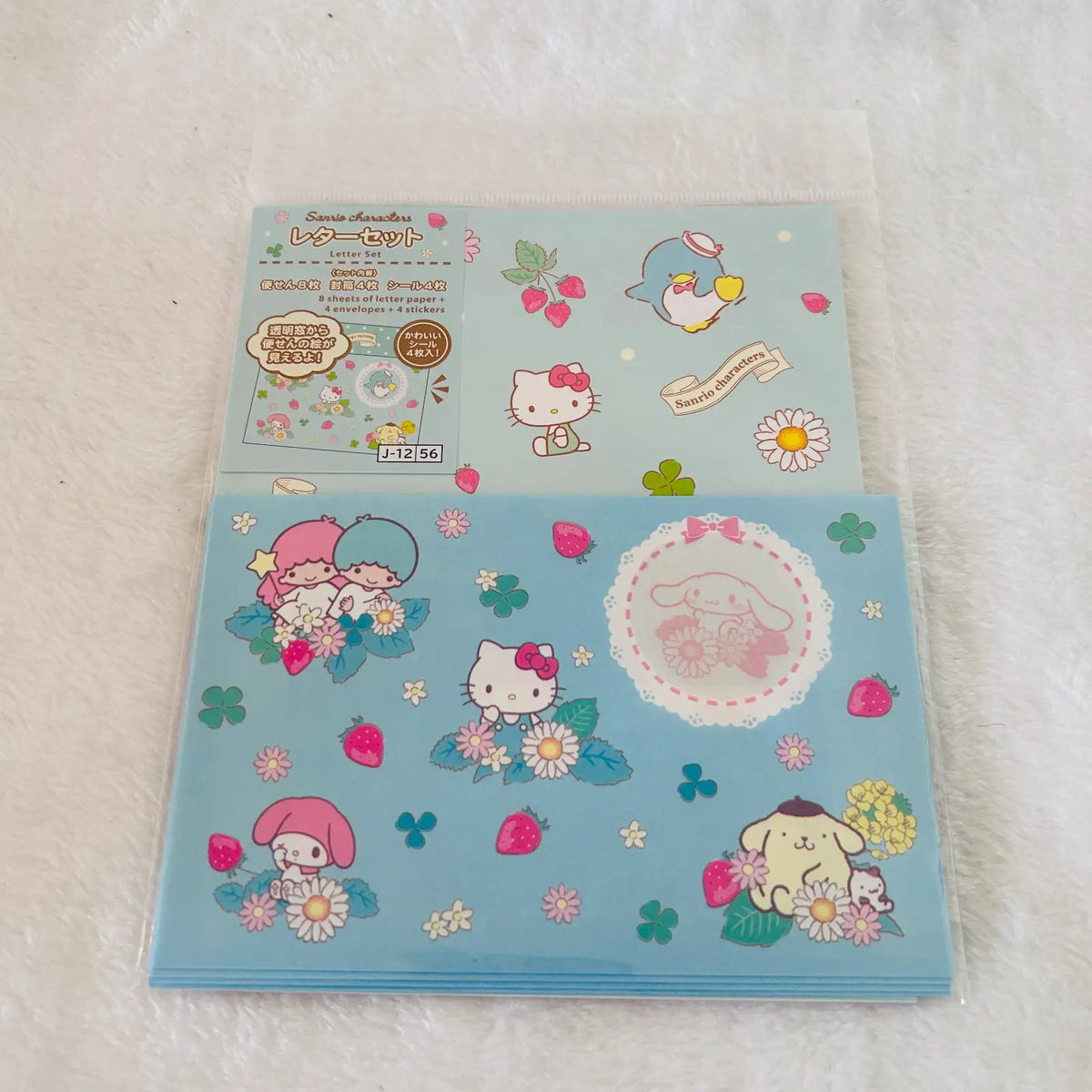 A stack of Sanrio Hello Kitty and Sanrio Cinnamoroll Letter Set, shows the product packaging with a Hello Kitty strawberry-themed design, and the bottom sheet displays the actual sticker collection featuring Hello Kitty, My Melody, Cinnamoroll, and a blue penguin.
