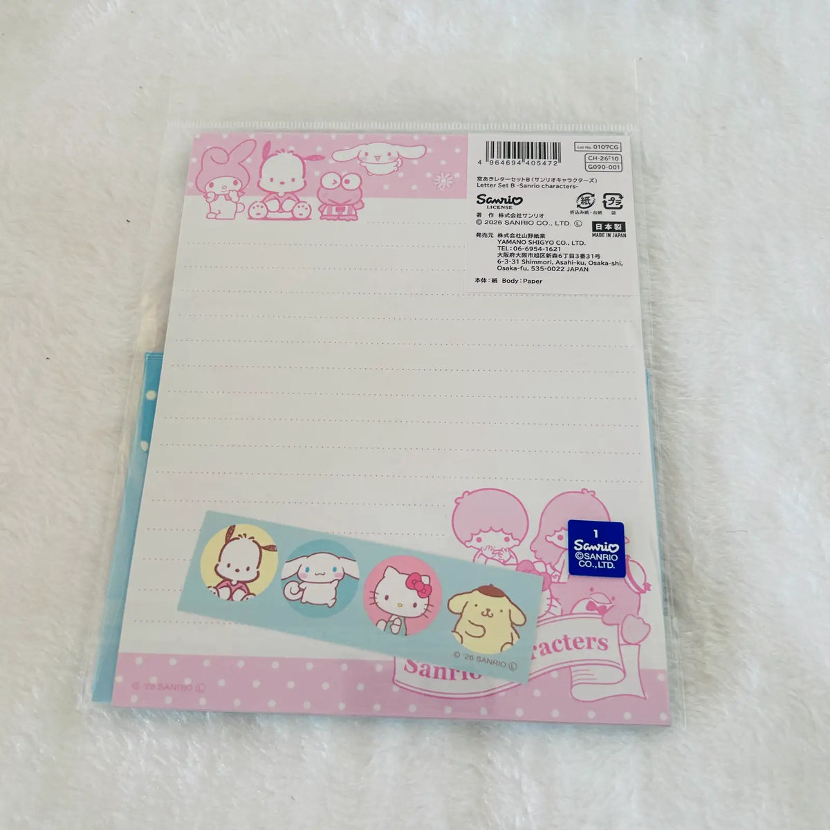 Sanrio Hello Kitty lined letter sheet with pink and blue borders, cartoon character illustrations, and a Sanrio logo, photographed on a white textured surface.