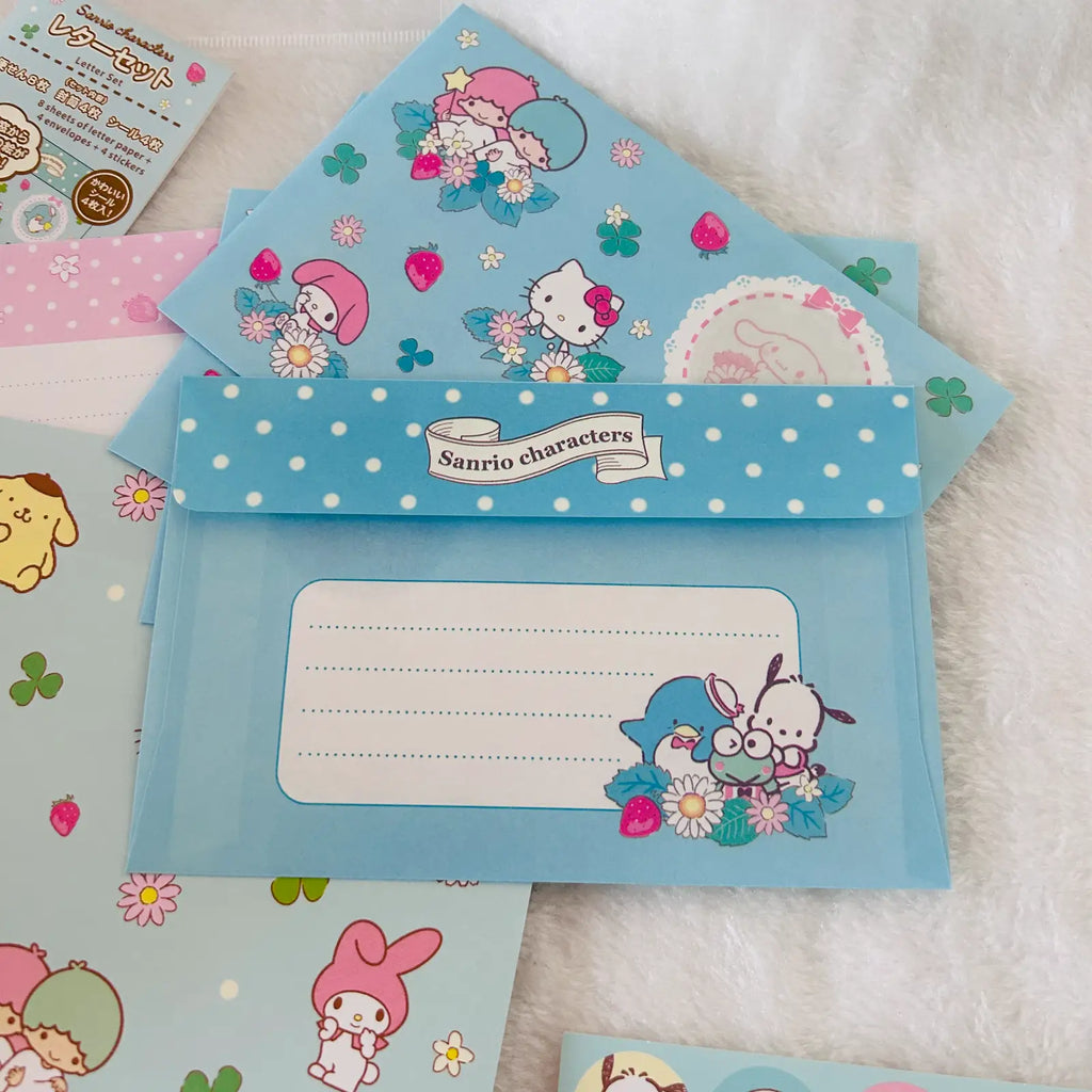 A set of pastel blue Sanrio character stationery items, including envelopes. The designs feature Hello Kitty, My Melody, and other Sanrio characters with flowers, clovers, and polka dots.
