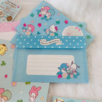A set of pastel blue Sanrio character stationery items, including envelopes. The designs feature Hello Kitty, My Melody, and other Sanrio characters with flowers, clovers, and polka dots.
