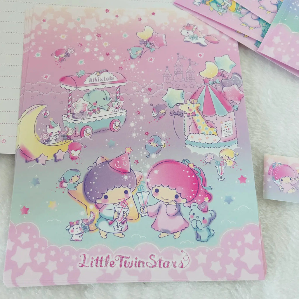 A pastel pink and lavender Little Twin Stars notebook or folder featuring cartoon characters, stars, and whimsical illustrations, placed on a white textured surface with other stationery items partially visible.