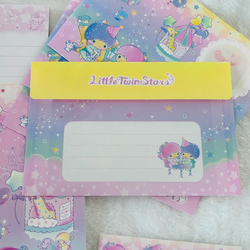 A stack of pastel pink and purple Little Twin Stars themed stationery items, including a translucent writing pad with a yellow header band and cartoon character illustrations, placed on a white fluffy surface.