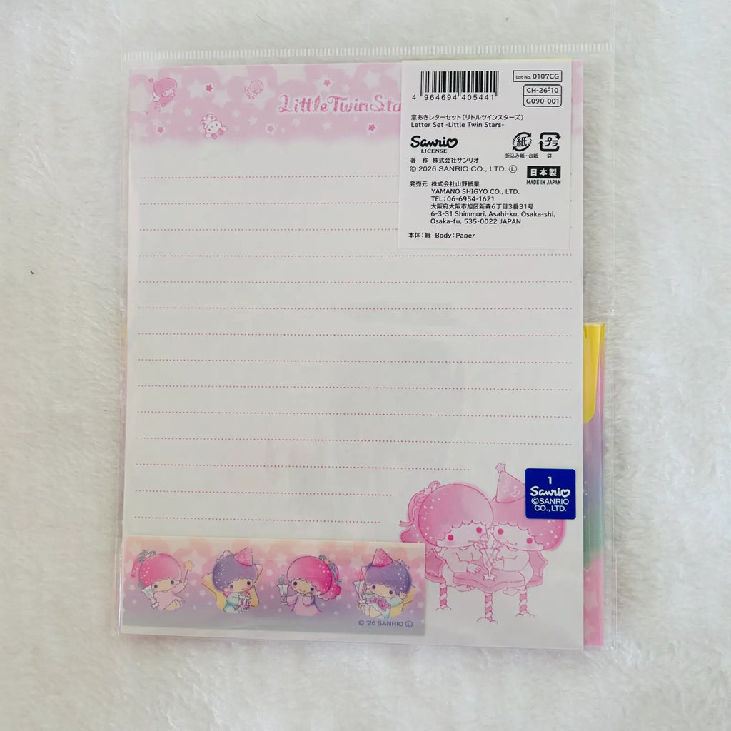 A Sanrio Little Twin Stars lined notepad sheet in a clear plastic sleeve, displayed on a white textured fabric background. The notepad features pink and pastel character illustrations, including Twin Stars and a pink bunny, with a blue Sanrio logo sticker in the bottom right corner.