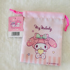 A pink My Melody drawstring pouch with a hanging tag, photographed on a soft white textured surface. The pouch features a printed illustration of My Melody with pink bows and stars, and the words 'My Melody' and 'Sanrio' are visible.