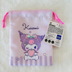 A light pink drawstring pouch featuring Kuromi from Sanrio, with a white product tag attached. The pouch has pink drawstrings, a printed illustration of Kuromi holding a pink heart, and a purple-and-white striped bottom border.