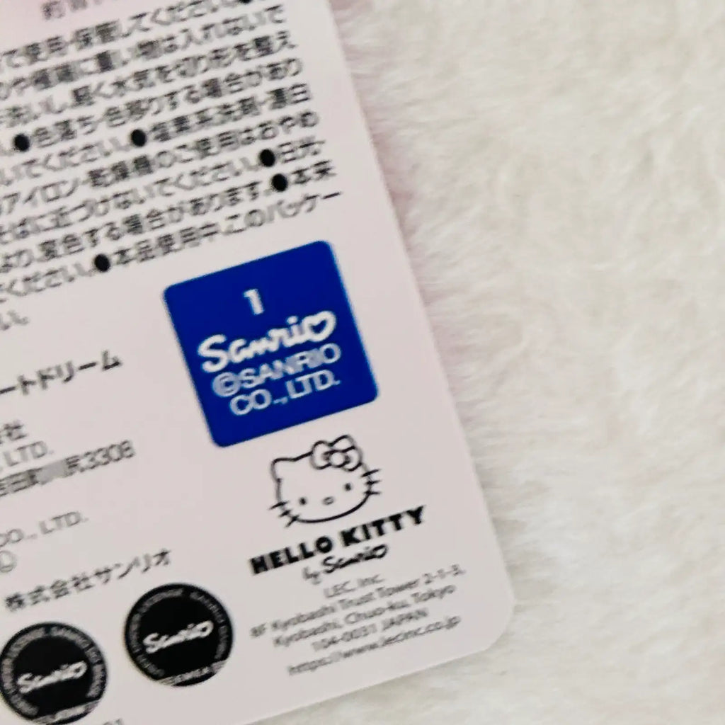 Close-up of the back of a Hello Kitty Sanrio product package, showing Japanese text, a blue Sanrio logo, a Hello Kitty line drawing, and a small circular Sanrio seal.