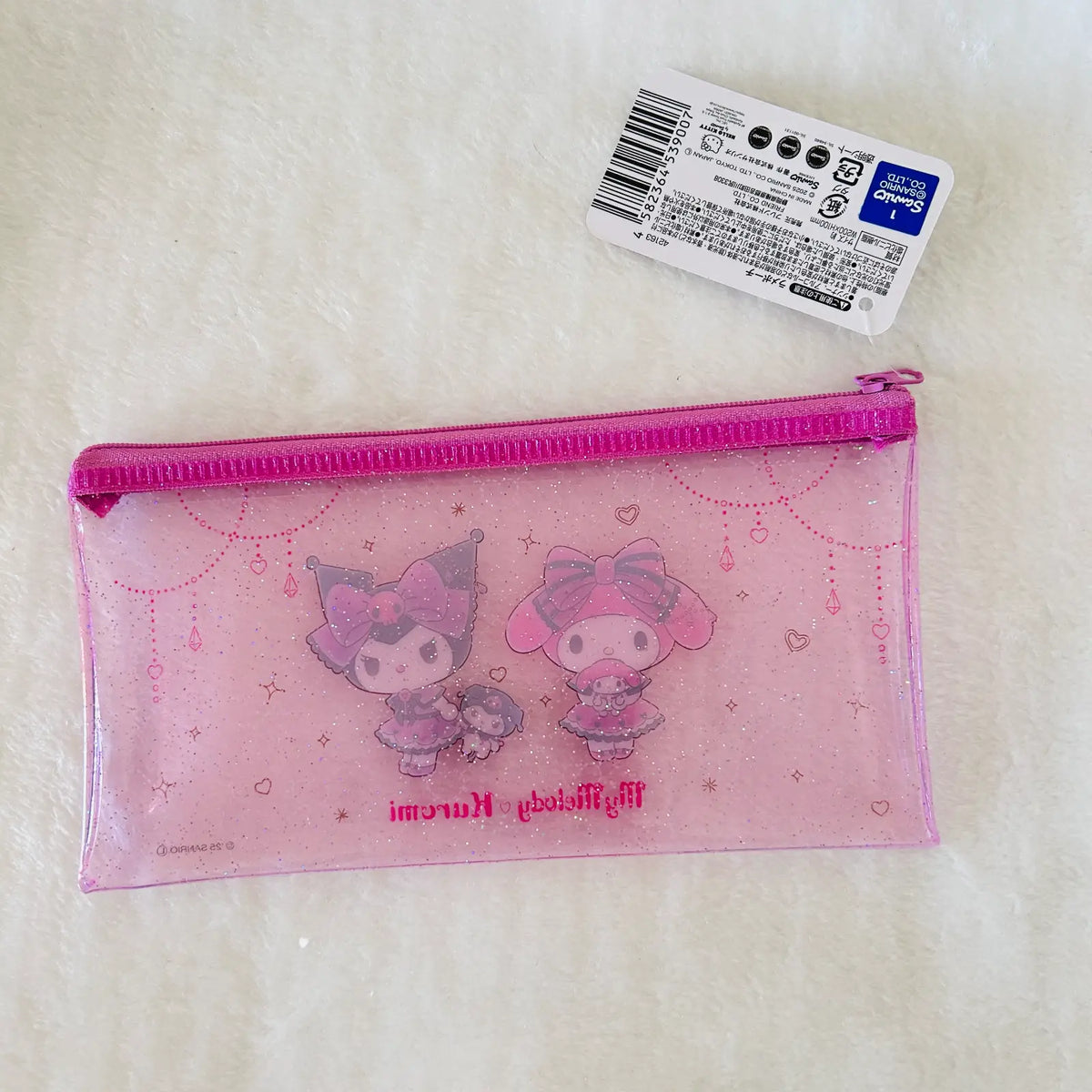 A pink translucent zippered pencil pouch featuring My Melody and Kuromi character illustrations, shown on a white textured surface with its product tag attached.