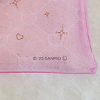 A close-up of a pink translucent plastic pouch with a white heart lattice pattern, gold heart and star outlines, and '© 25 SANRIO' printed near the bottom, resting on a white textured surface.