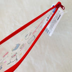 A clear plastic pencil case with a bright red zipper and red loop, decorated with cute cartoon characters and Japanese text.