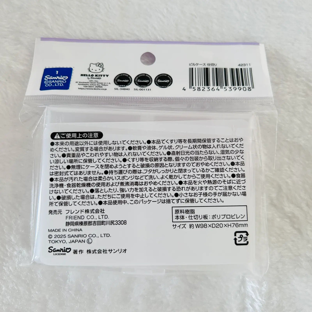 A packaged Sanrio Hello Kitty product in a clear plastic bag with a printed white backing card. The card shows the Sanrio and Hello Kitty logos, a barcode, and multiple lines of Japanese warning and product information.
