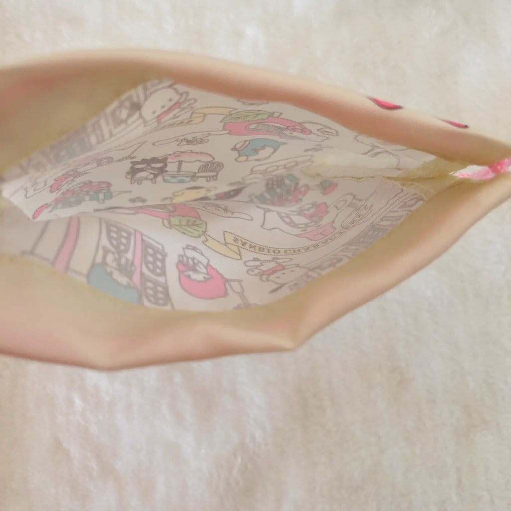 A close-up of a beige fabric pouch or bag with a colorful cartoon character print lining the interior, photographed on a soft white textured background.