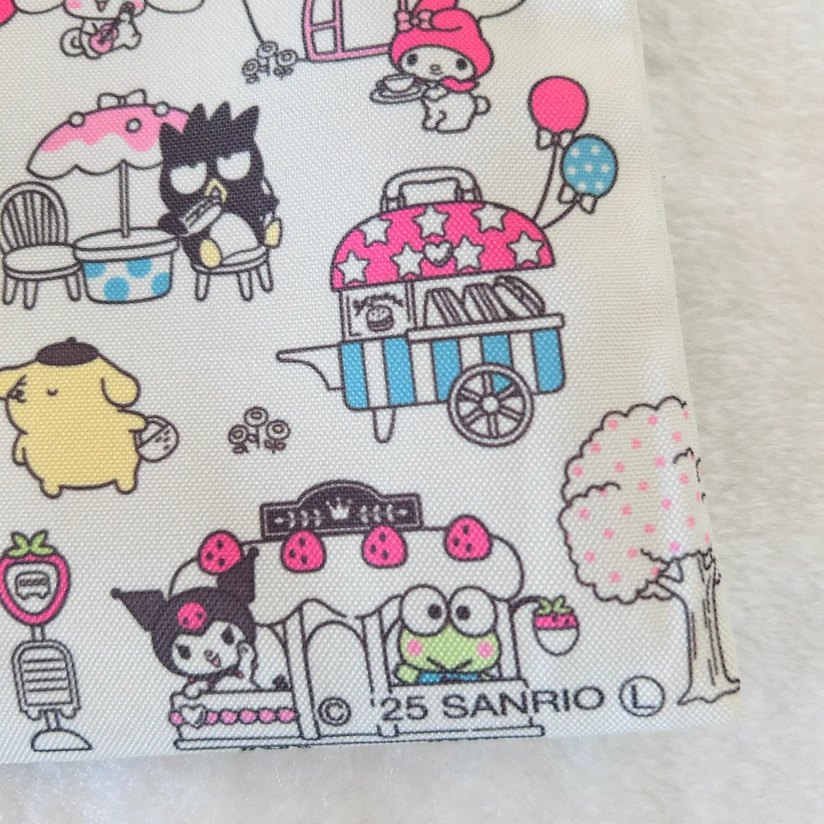 A close-up of a fabric or paper print featuring Sanrio character illustrations, including Kuromi, My Melody, and Pompompurin, in a picnic-themed pattern on a white background.