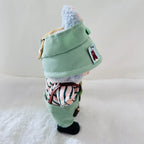 A Labubu doll wearing a mint green bucket hat with a patch, a striped shirt, and green pants.