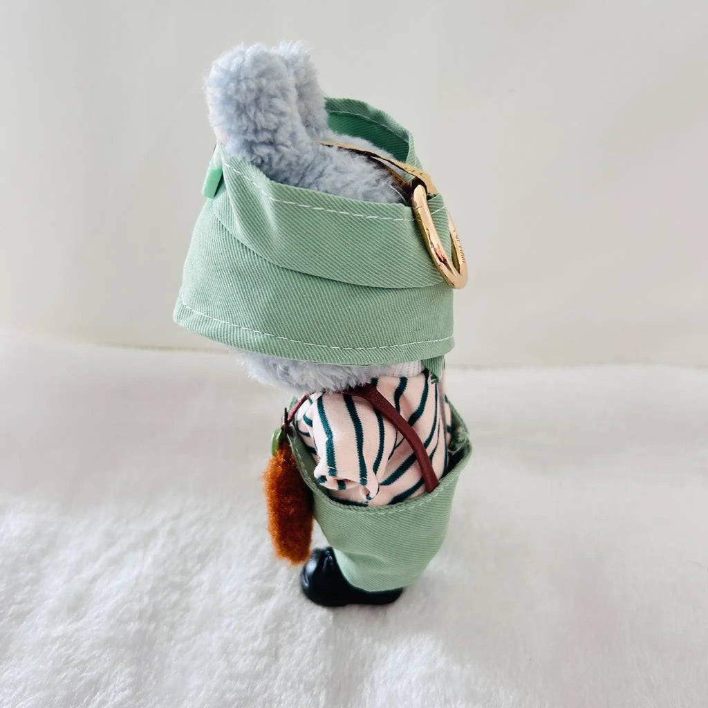 A Labubu doll dressed in a mint green fabric harness-style outfit with a striped shirt, brown harness straps.