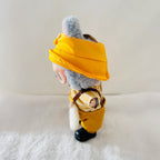 A Labubu plush toy wearing a bright yellow hat and matching yellow outfit, standing on a white textured surface.