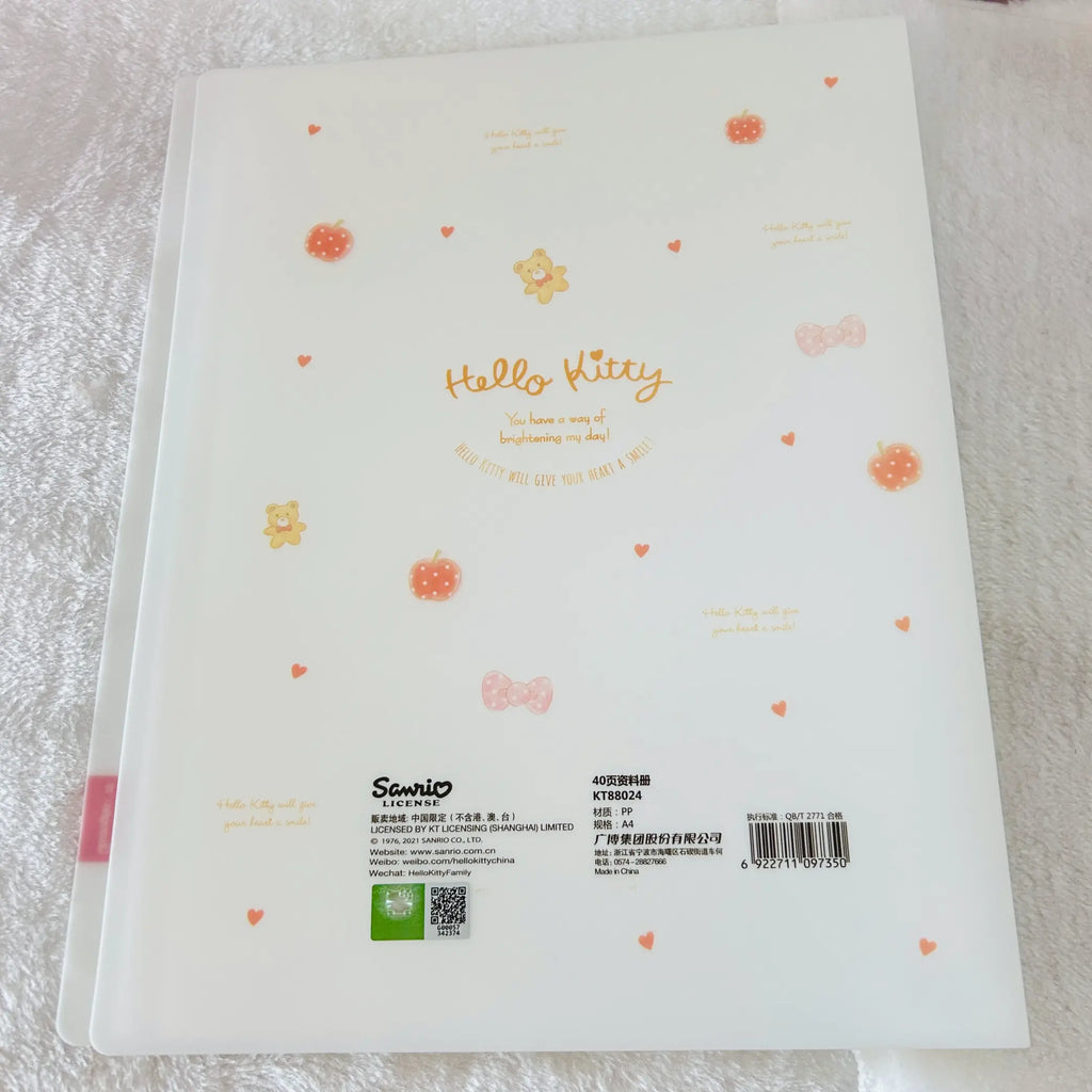 A white Hello Kitty 40-page clear book back cover by Sanrio, decorated with small orange flowers, hearts, and bows, shown on a textured white fabric background.