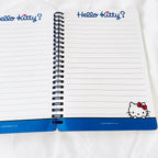 An open Hello Kitty spiral notebook with lined pages, blue header text reading 'Hello Kitty?' at the top, and a blue bottom band featuring a Hello Kitty illustration.