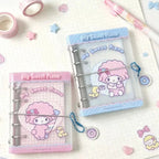 Two clear plastic binder covers with 'My Sweet Piano' character artwork, displayed on a white grid notebook with pastel stationery accessories.