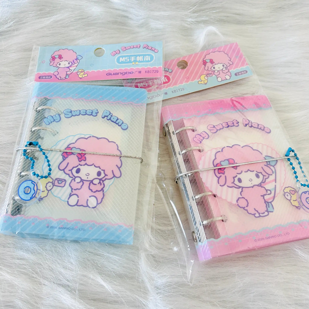 Two packaged My Sweet Piano ring-bound planner. One package contains a blue-themed page and charm, and the other contains a pink-themed page and charm, both with Sanrio-style character artwork.