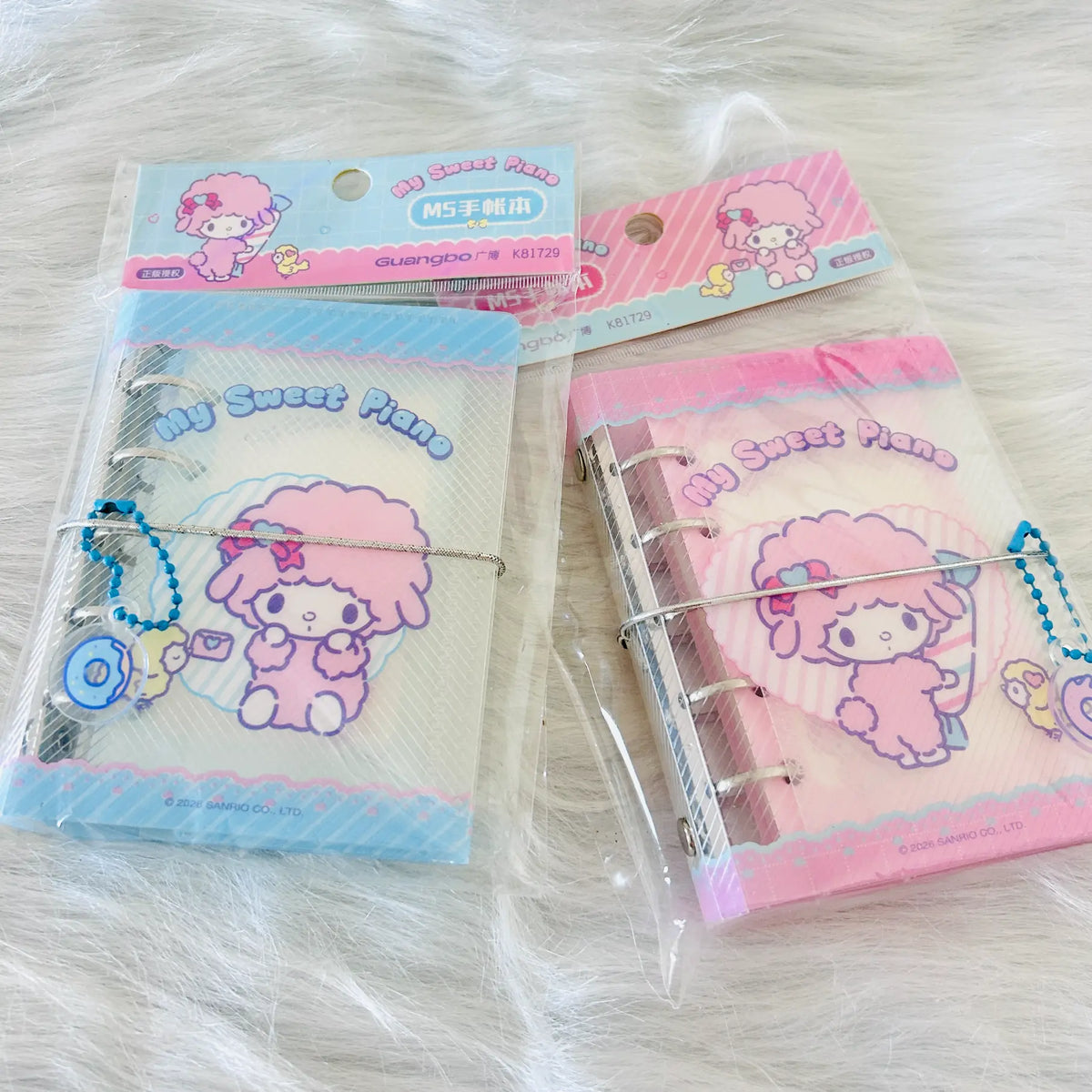 Two packaged My Sweet Piano ring-bound planner. One package contains a blue-themed page and charm, and the other contains a pink-themed page and charm, both with Sanrio-style character artwork.