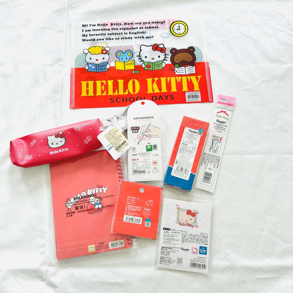A flat lay of Hello Kitty school accessories, including a red pencil case, a red notebook, a red pen, etc.