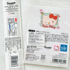 A sealed Sanrio Hello Kitty product package photographed on a white background, showing the back of the packaging with Japanese text, a cartoon Hello Kitty illustration, barcode, QR code, and a blue Sanrio logo block.