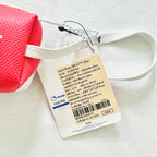 A close-up of a pink textured bag with a white strap and a hanging product tag. The tag shows the Hello Kitty Sanrio branding and product details in Thai text.