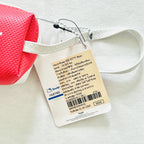 A close-up of a pouch with a white strap and a paper hangtag. The tag shows Hello Kitty branding and product details in English and Thai.