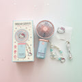 Hello Kitty portable handheld fan set with its retail box, featuring a pastel pink and light blue fan, a matching beaded wrist strap with a Hello Kitty charm, a USB charging cable, and a small Hello Kitty card.