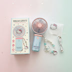Hello Kitty portable handheld fan set with its retail box, featuring a pastel pink and light blue fan, a matching beaded wrist strap with a Hello Kitty charm, a USB charging cable, and a small Hello Kitty card.
