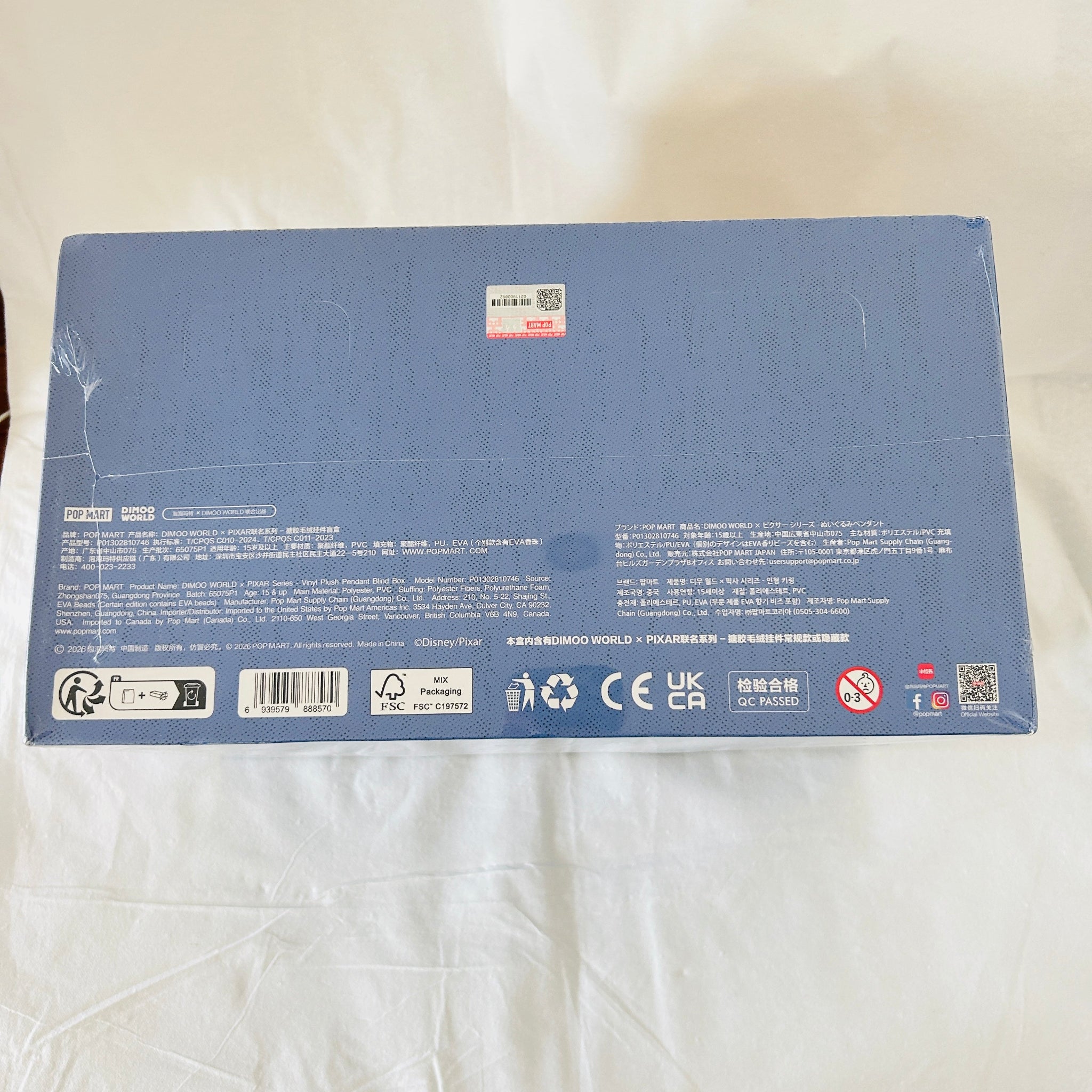 The back of a blue rectangular product box. The box contains small printed text, barcodes, recycling symbols, and compliance marks.