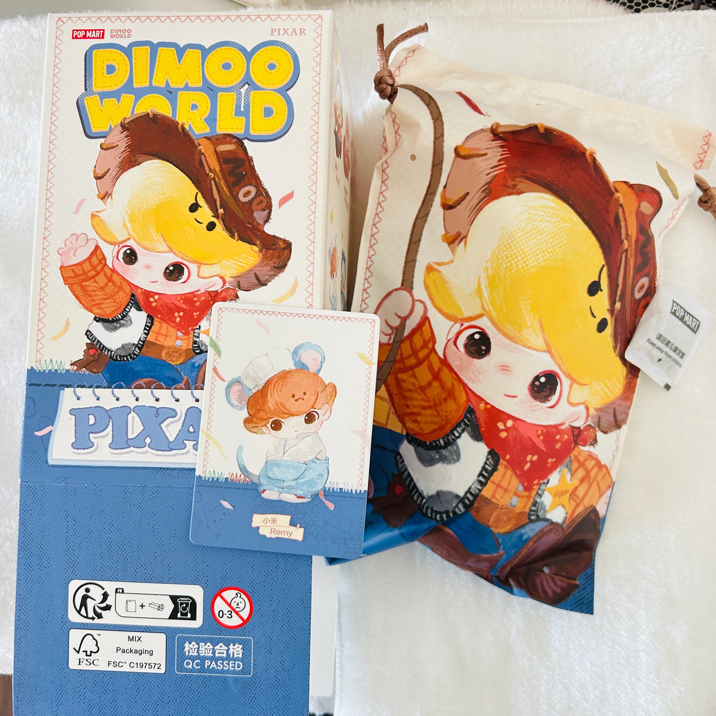 Dimoo World Pixar-themed character merchandise set featuring a character art box, a matching pouch, and a small card displaying Remy. 