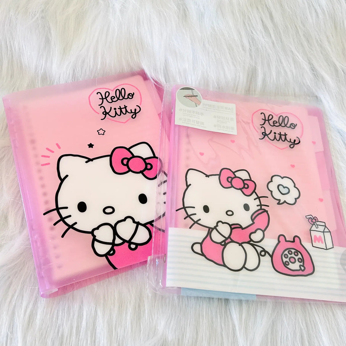 Two pink Hello Kitty plastic binder notebooks One showing a big Hello Kitty's face,  while another showing a Kitty talking on phone.
