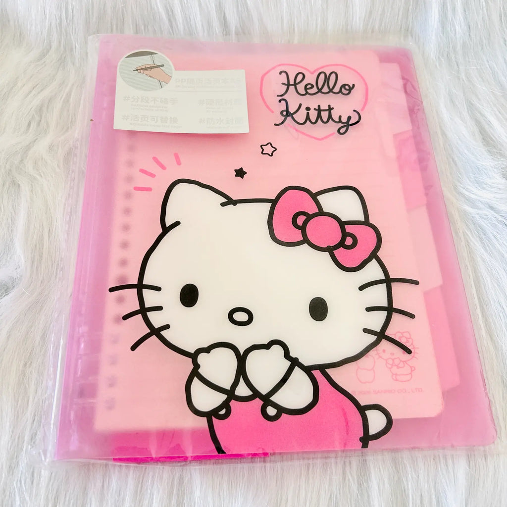 A pink Hello Kitty ring binder notebook in its clear plastic packaging, featuring a large white Hello Kitty character illustration with a pink bow on the cover.