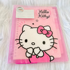 A pink Hello Kitty ring binder notebook in its clear plastic packaging, featuring a large white Hello Kitty character illustration with a pink bow on the cover.