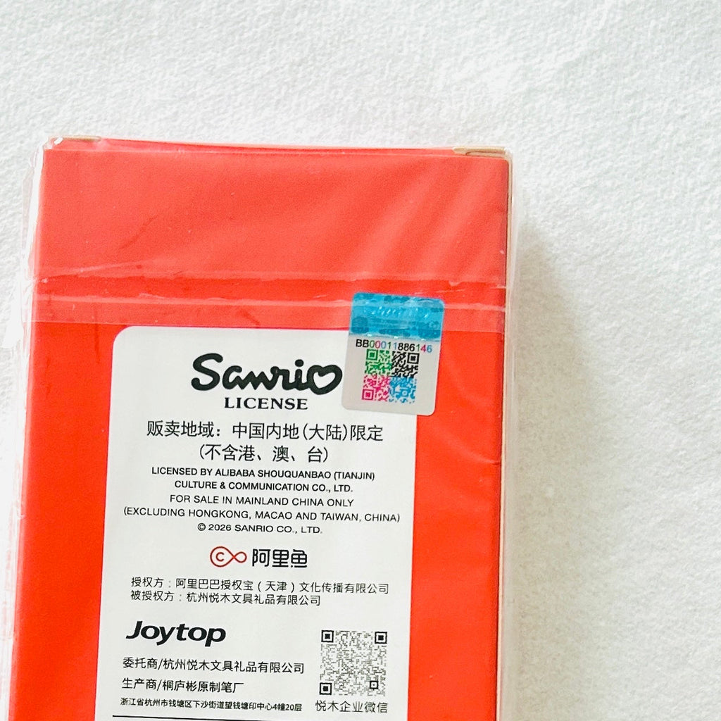 A red rectangular product package with a large white label reading Sanrio License and Joytop, photographed on a light textured background.