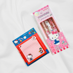 Hello Kitty stationery set including a pink memo pad in blue packaging and a pink pen set in a clear windowed box, both featuring Hello Kitty illustrations on a white fabric background.