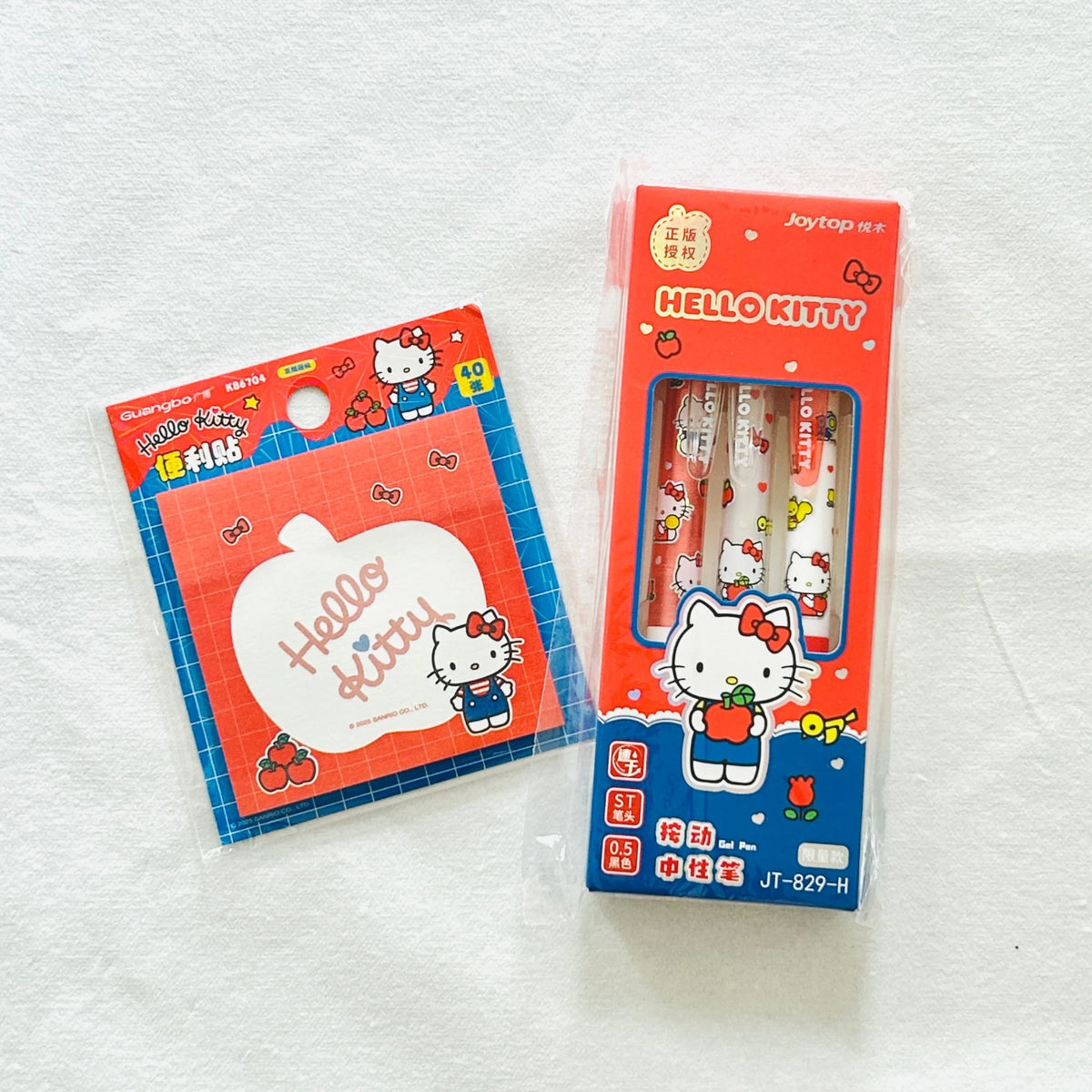 Hello Kitty stationery set featuring a red box of three gel pens and a notepad, both decorated with Hello Kitty illustrations. 