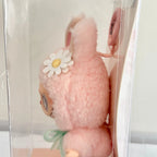 A close-up view of the pink Labubu Mokoko, featuring a white daisy flower  on its head and a small mint green bow at the neck.