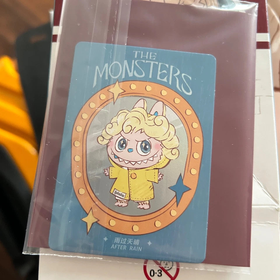 A packaged collectible card featuring a cartoon monster character in a yellow raincoat on a blue card, sealed in a clear plastic sleeve and resting on a white surface.