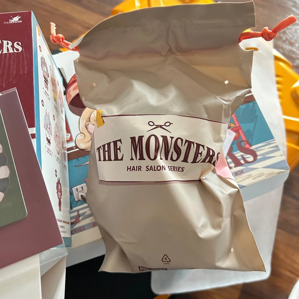 A drawstring pouch labeled 'THE MONSTERS HAIR SALON SERIES' with red drawstring ties