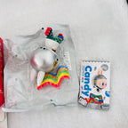A Popdits Candy Rainbow Cave Shark figure in its clear plastic packaging, shown next to its illustrated card packaging on a white faux fur surface.